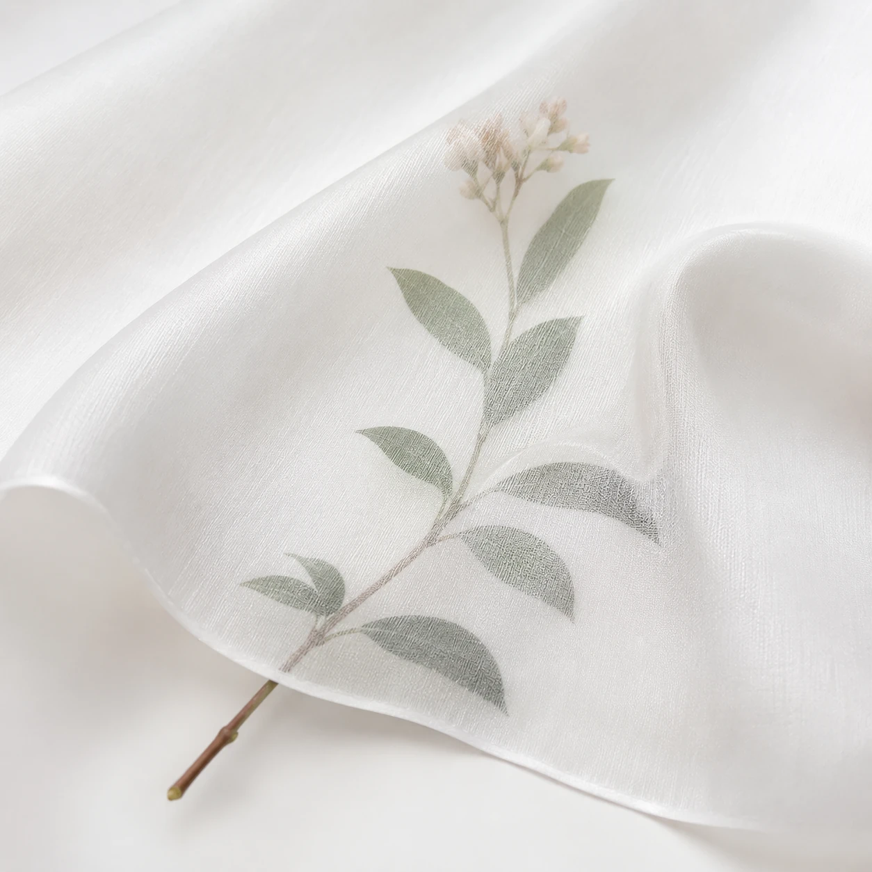 White silk twill fabric with soft drape texture and a subtle botanical stem visible underneath.