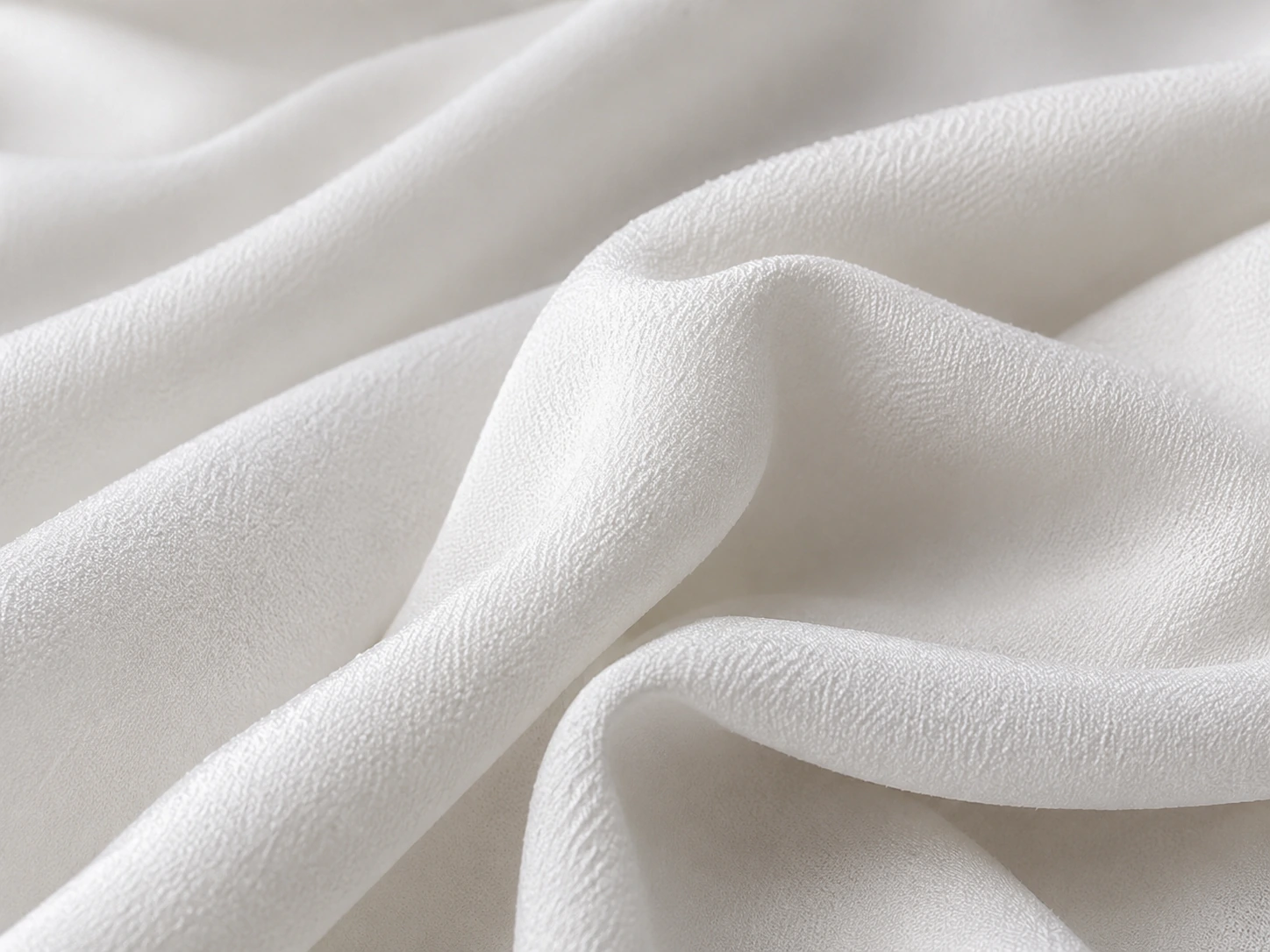 White silk crepe de chine fabric closeup with soft matte texture and folds