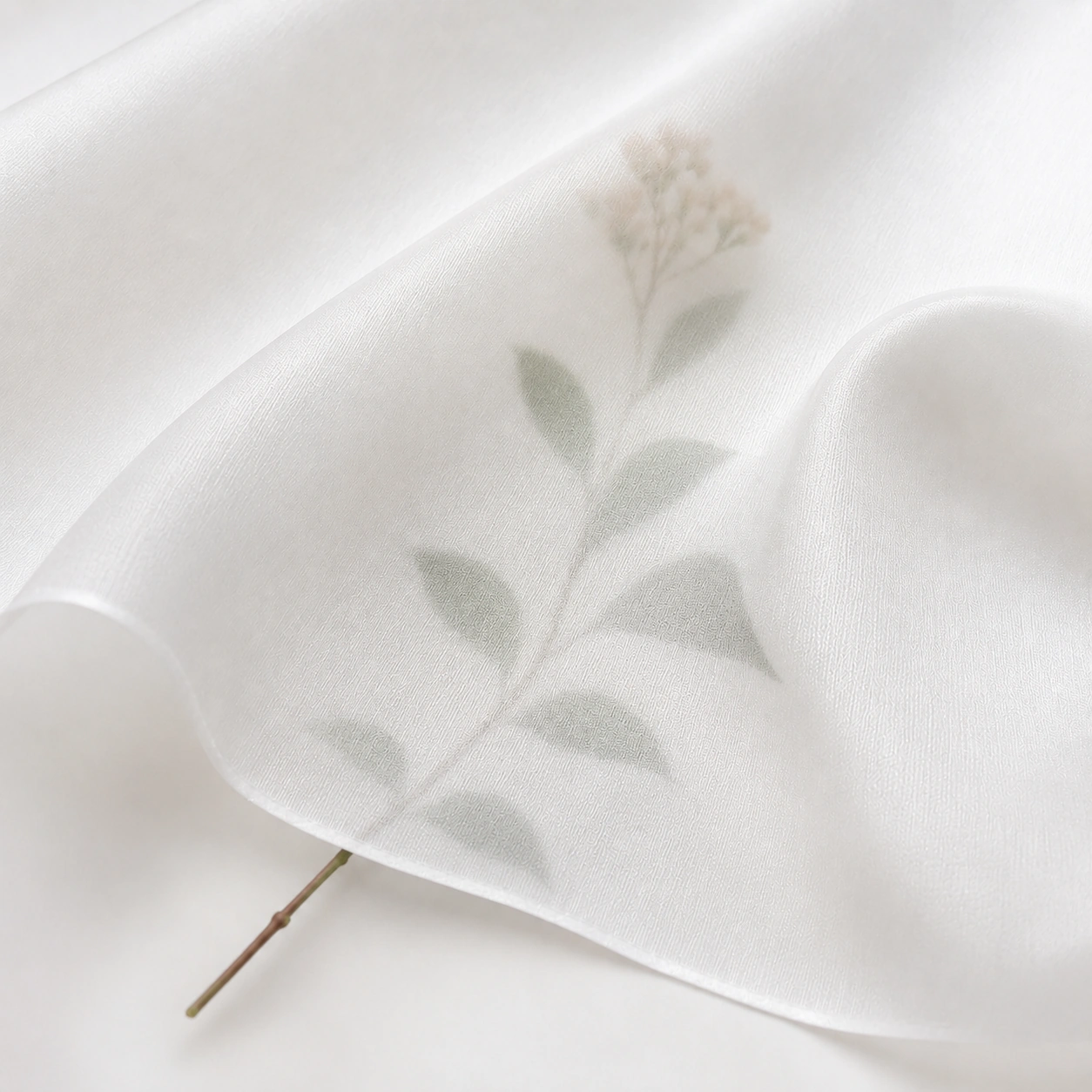 White silk twill fabric showing transparency detail with a visible botanical stem and leaf pattern underneath.