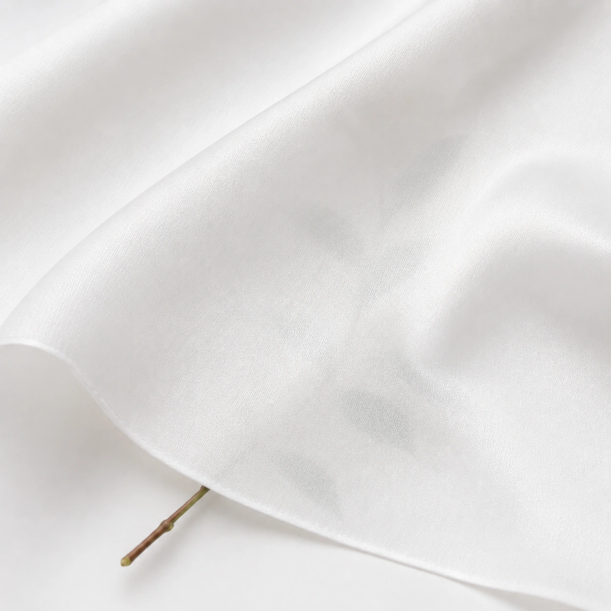 White silk twill fabric with a light transparency effect and a subtle leaf silhouette beneath.