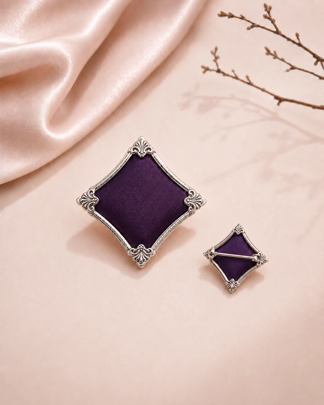 Diamond-shaped purple silk brooch with ornate silver frame and visible back pin