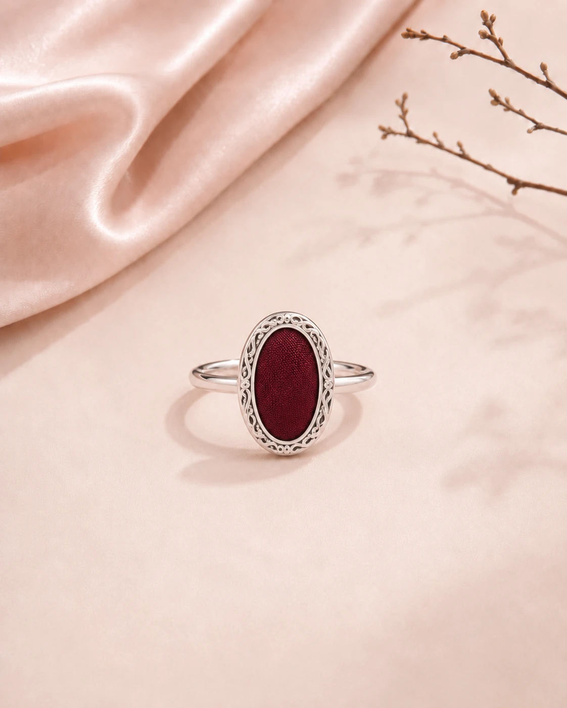Oval ring with solid burgundy silk center and ornate silver-tone metal decoration